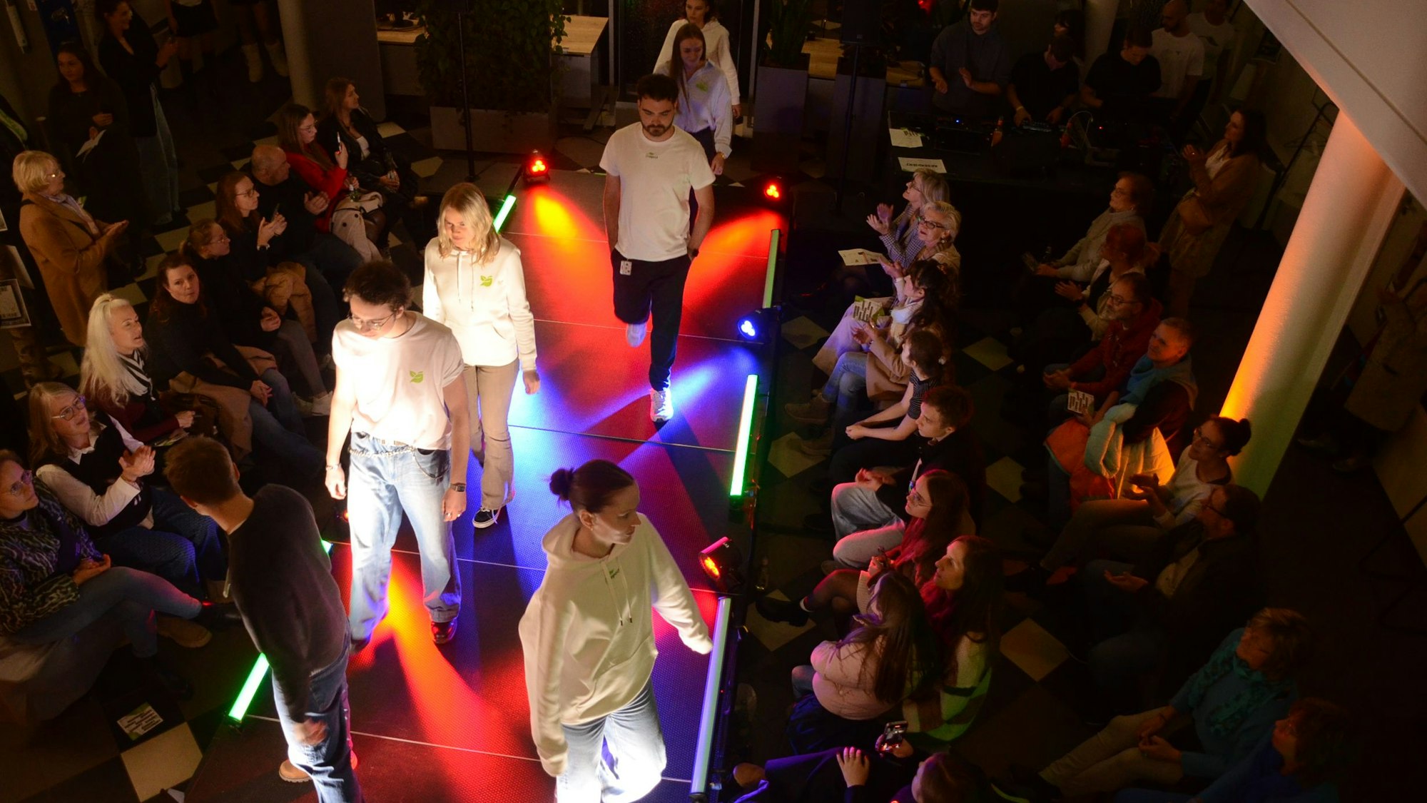 Junge Menschen in weißer Kleidung auf dem Laufsteg einer Modenschau.