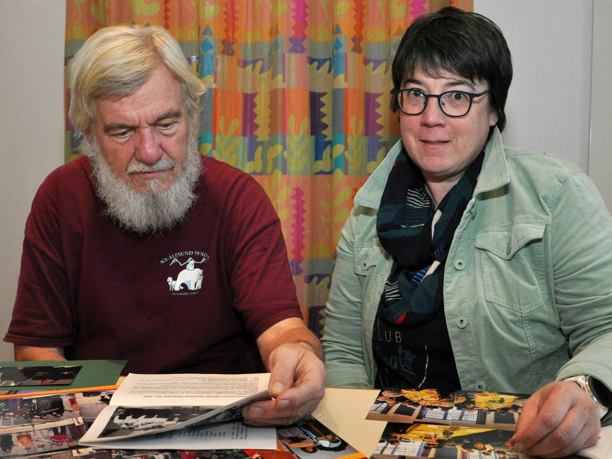 Ein Mann und eine Frau schauen Fotos und Dokumente durch.