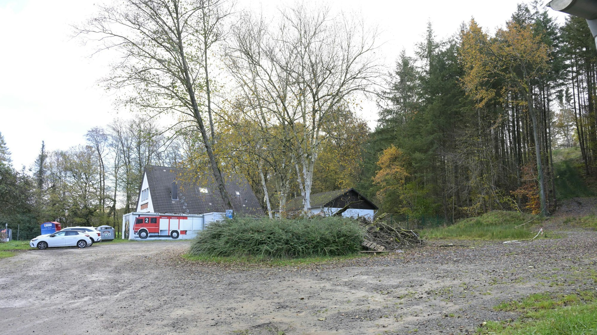 Ein Schotterparkplatz, dahinter ein Feuerwehrhaus.