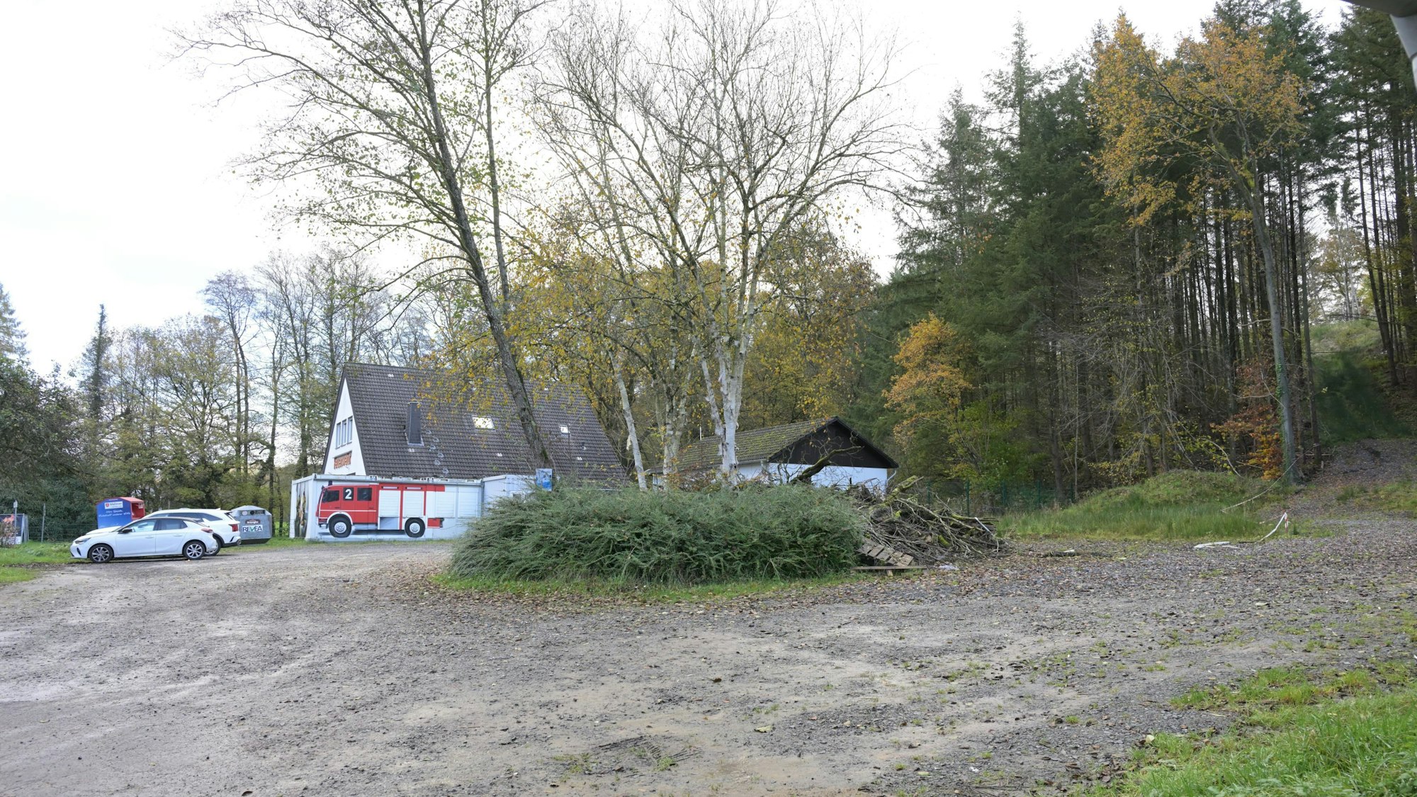 Ein Schotterparkplatz neben einem Feuerwehrgerätehaus.