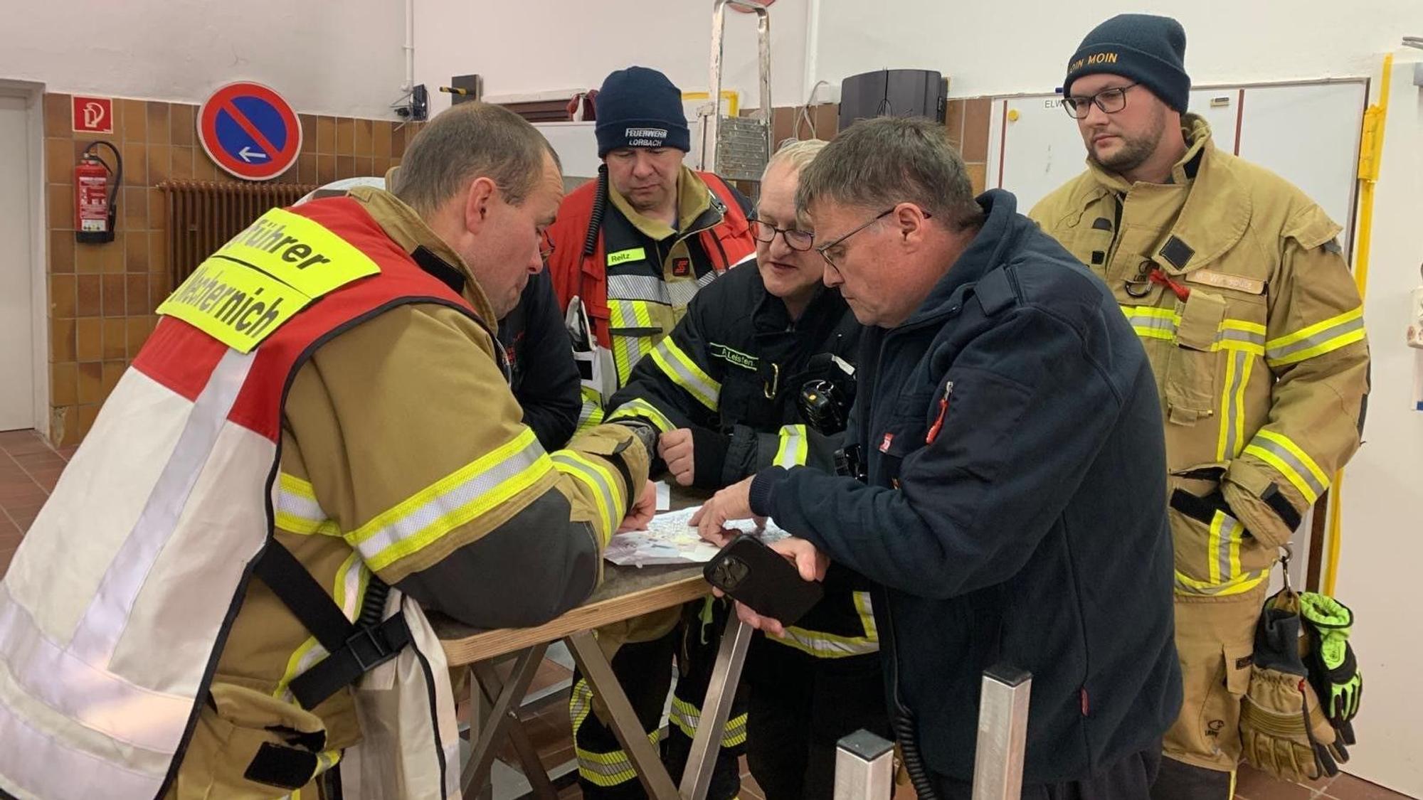 Das Bild zeigt einige Feuerwehrleute während einer Lagebesprechung.