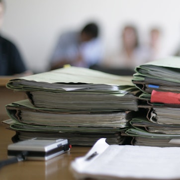 Aktenordner liegen im Gerichtssaal zu Beginn einer Verhandlung auf dem Tisch.