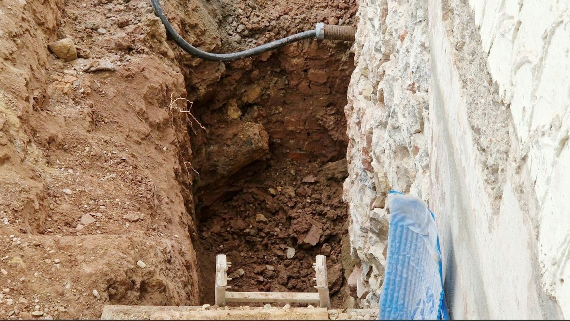 Im Boden an einer Häuserwand befindet sich die freigelegte Fliegerbombe.