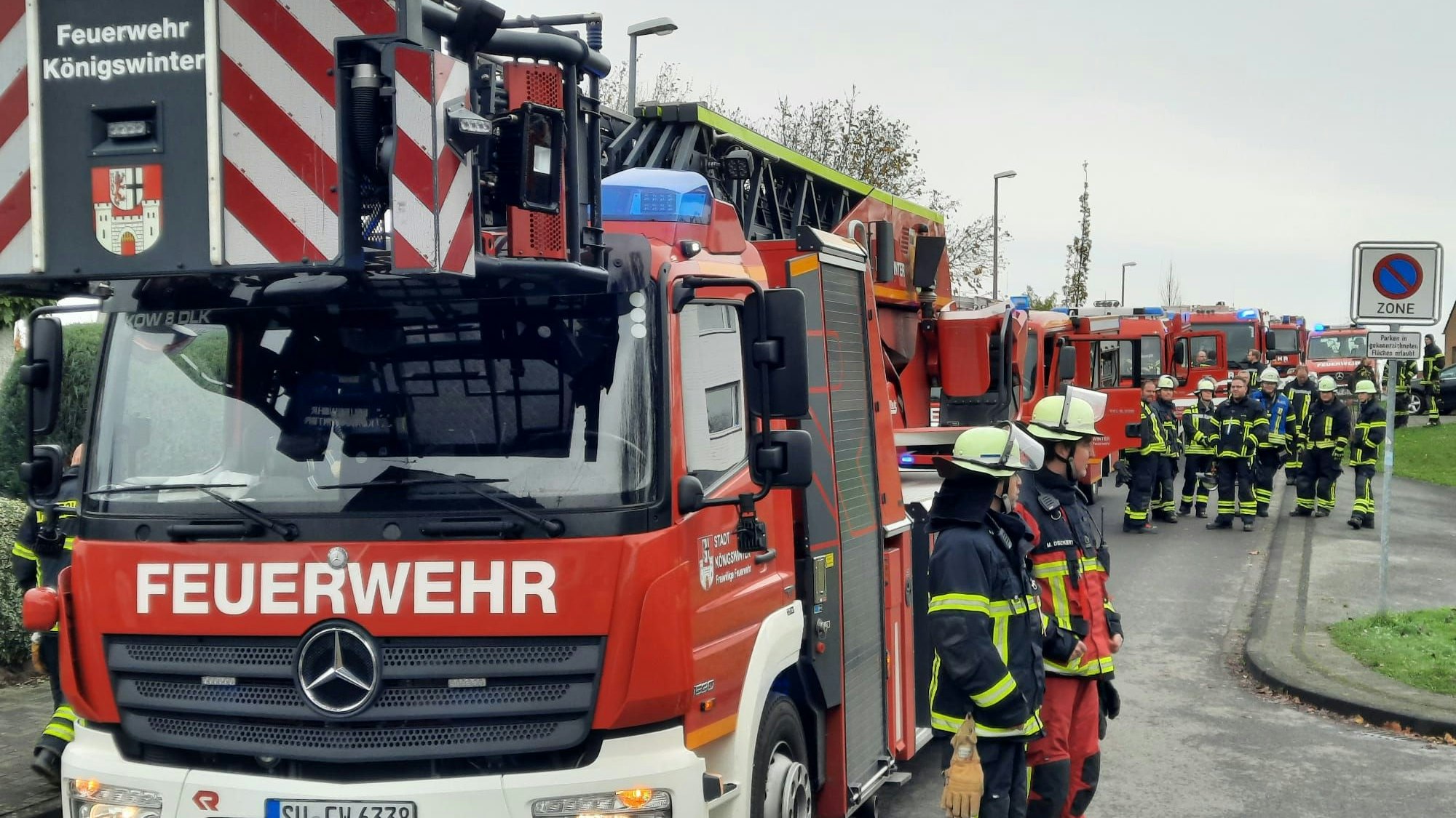 Hinter der Drehleiter stehen zahlreiche Fahrzeuge der Feuerwehr.