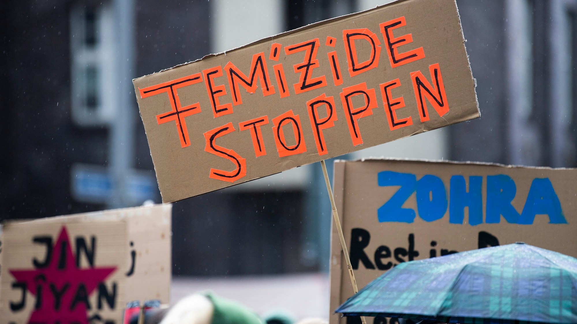 Bei einer Demonstration gegen Gewalt an Frauen hält eine Teilnehmerin ein Plakat mit der Aufschrift „Femizide stoppen“.