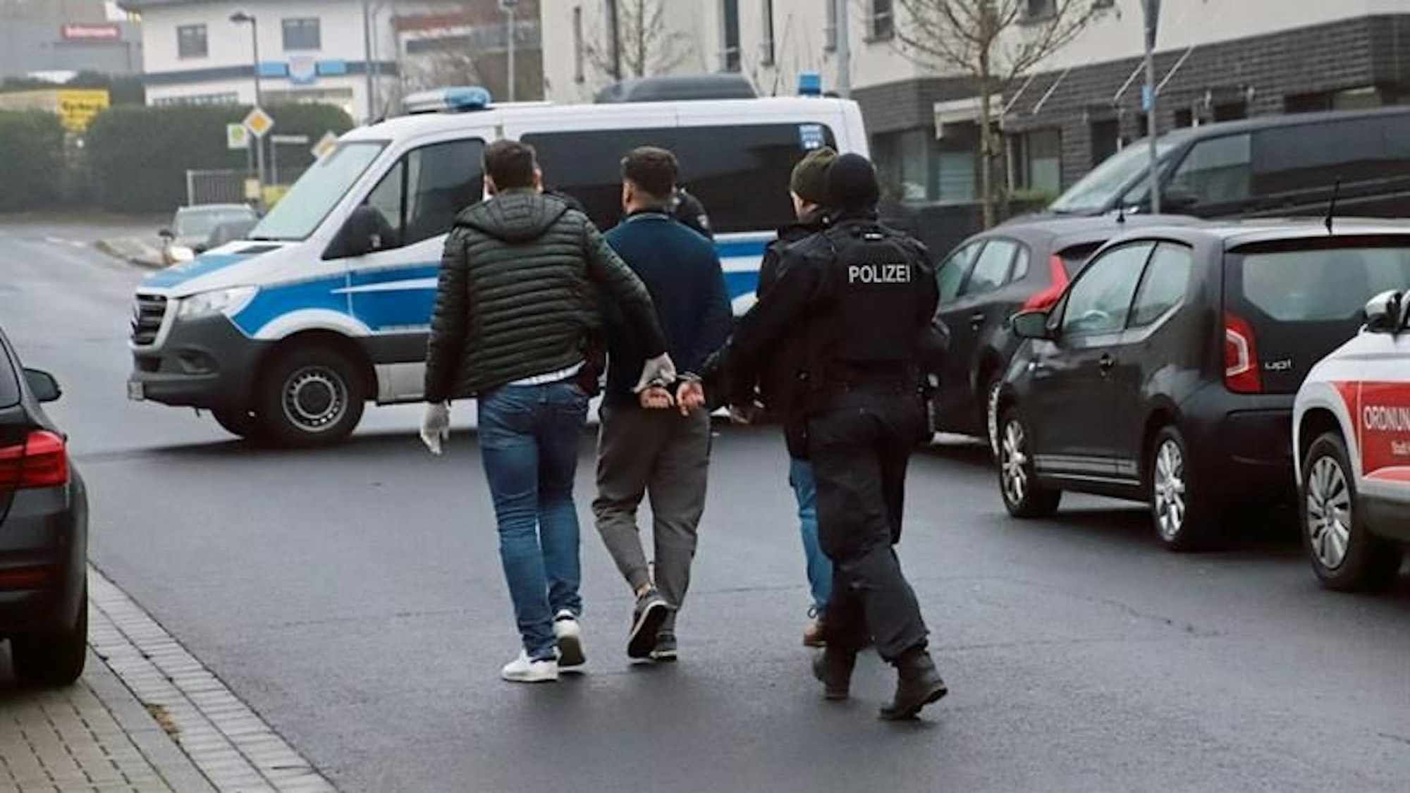 Die Polizei führt bei der Razzia wegen gefälschten Sprachzertifikaten  in Hennef-Hossenberg einen Verdächtigen ab.