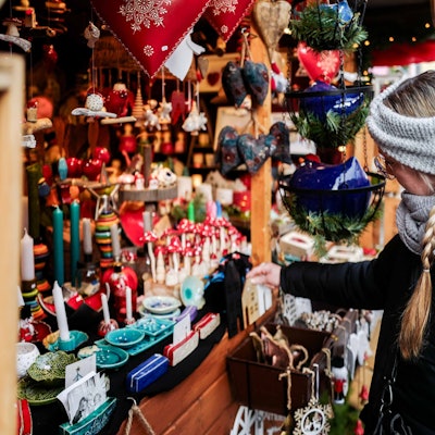 Das Bild zeigt eine Frau, die sich Deko an einer Weihnachtsbude anschaut.