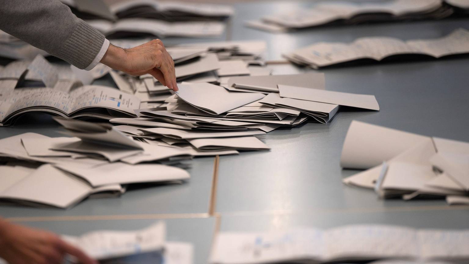 Wahlhelfer und Wahlhelferinnen zählen in einem Wahllokal Stimmzettel für die Bundestagswahl aus.