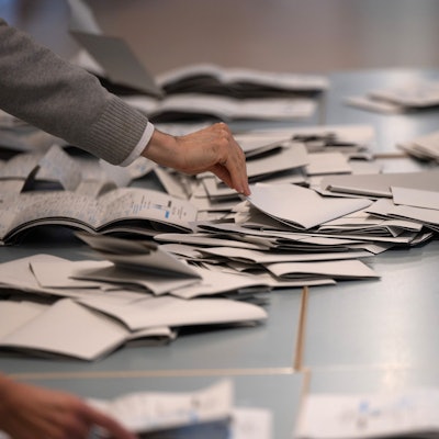 Wahlhelfer und Wahlhelferinnen zählen in einem Wahllokal Stimmzettel für die Bundestagswahl aus.