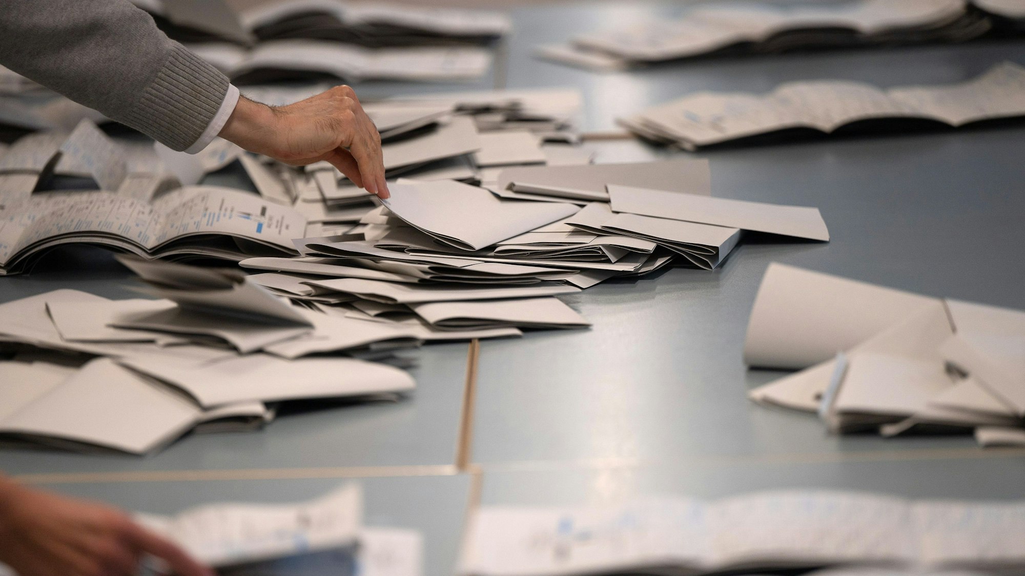 Wahlhelfer und Wahlhelferinnen zählen in einem Wahllokal Stimmzettel für die Bundestagswahl aus.