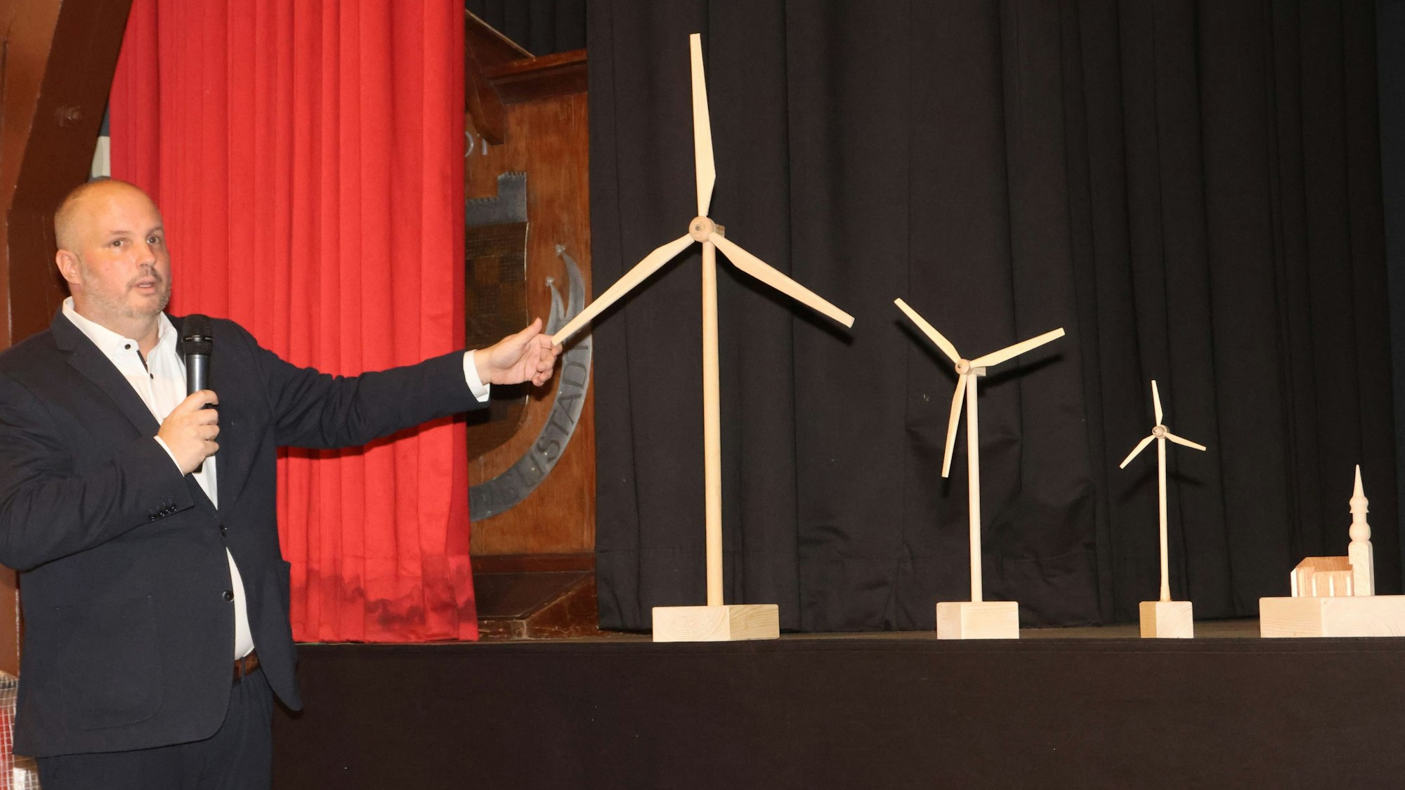 Bergneustadts Bürgermeister Matthias Thul demonstriert das Größenverhältnis der neuen Windräder im Vergleich zu bestehenden Gebäuden