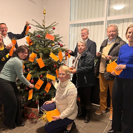 Bürgermeister Dirk Runge, Tenneco-Geschäftsführer Thomas Ebker und Annika Wiertz, Sprecherin von Adient stehen an einem Weihnachtsbaum.