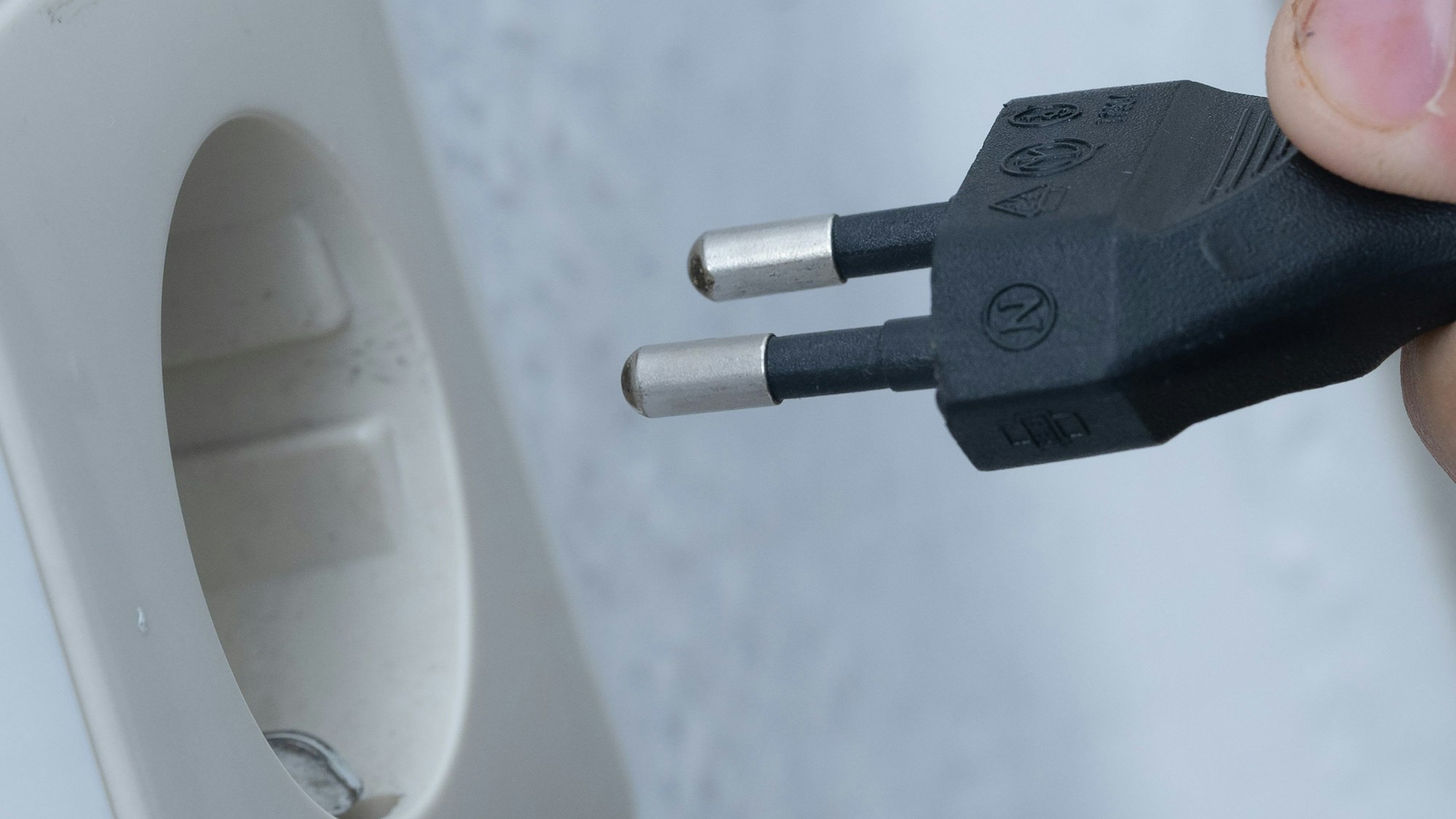 Ein Mann steckt einen Stecker in eine Steckdose.