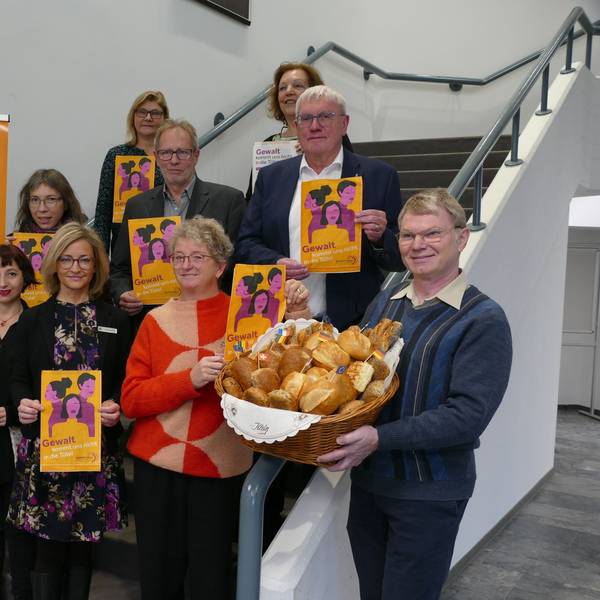 Mehrere Menschen stehen auf einer Treppe und halten Tüten sowie einen Brötchenkorb hoch.
