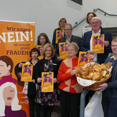Mehrere Menschen stehen auf einer Treppe und halten Tüten sowie einen Brötchenkorb hoch.