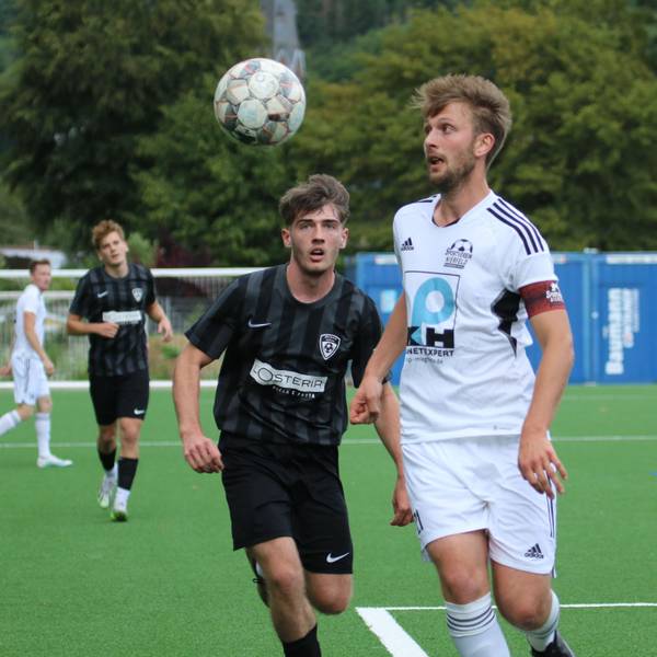 Zwei Fußballer fixieren mit den Augen den herannahenden Ball.
