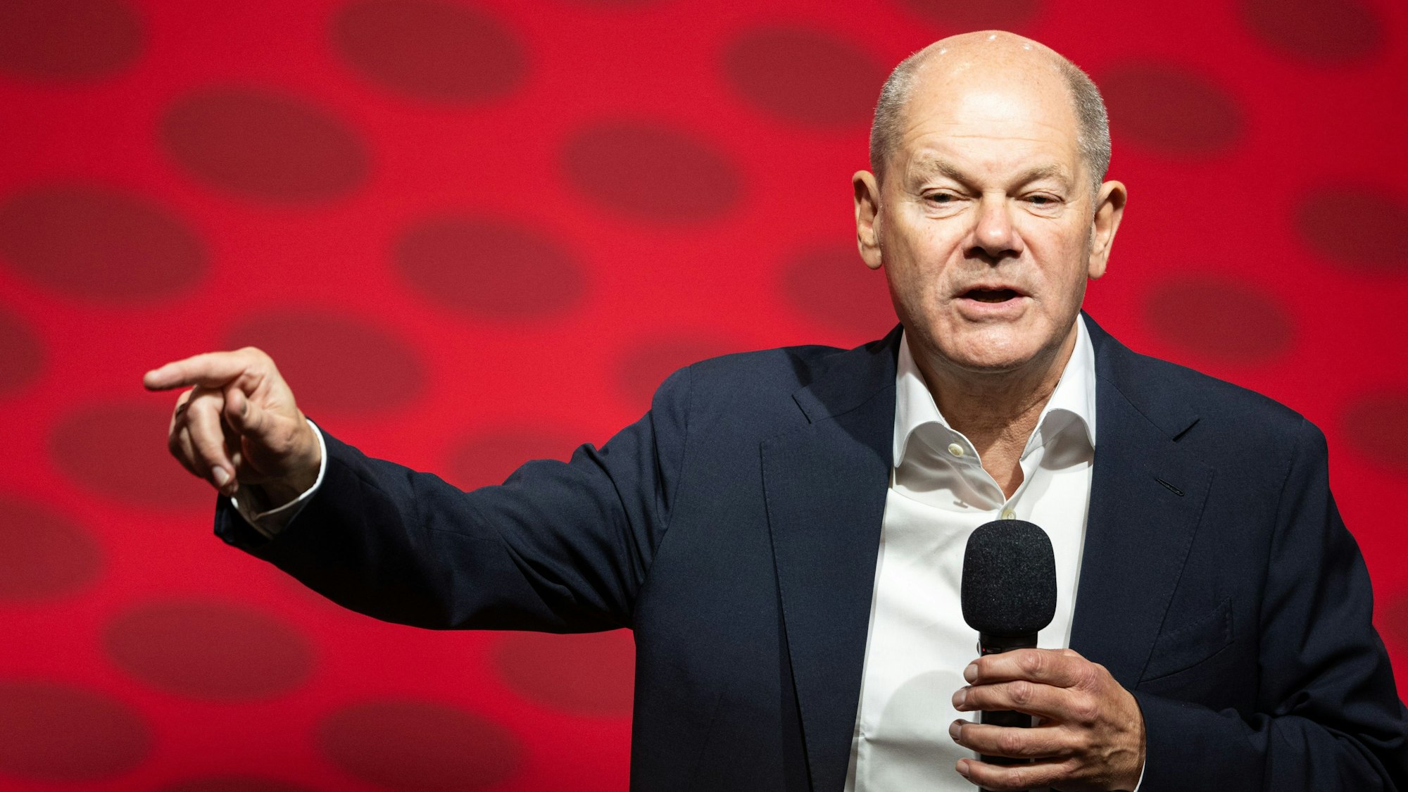 Olaf Scholz bei einer Rede, mit Mikrofon in der Hand.