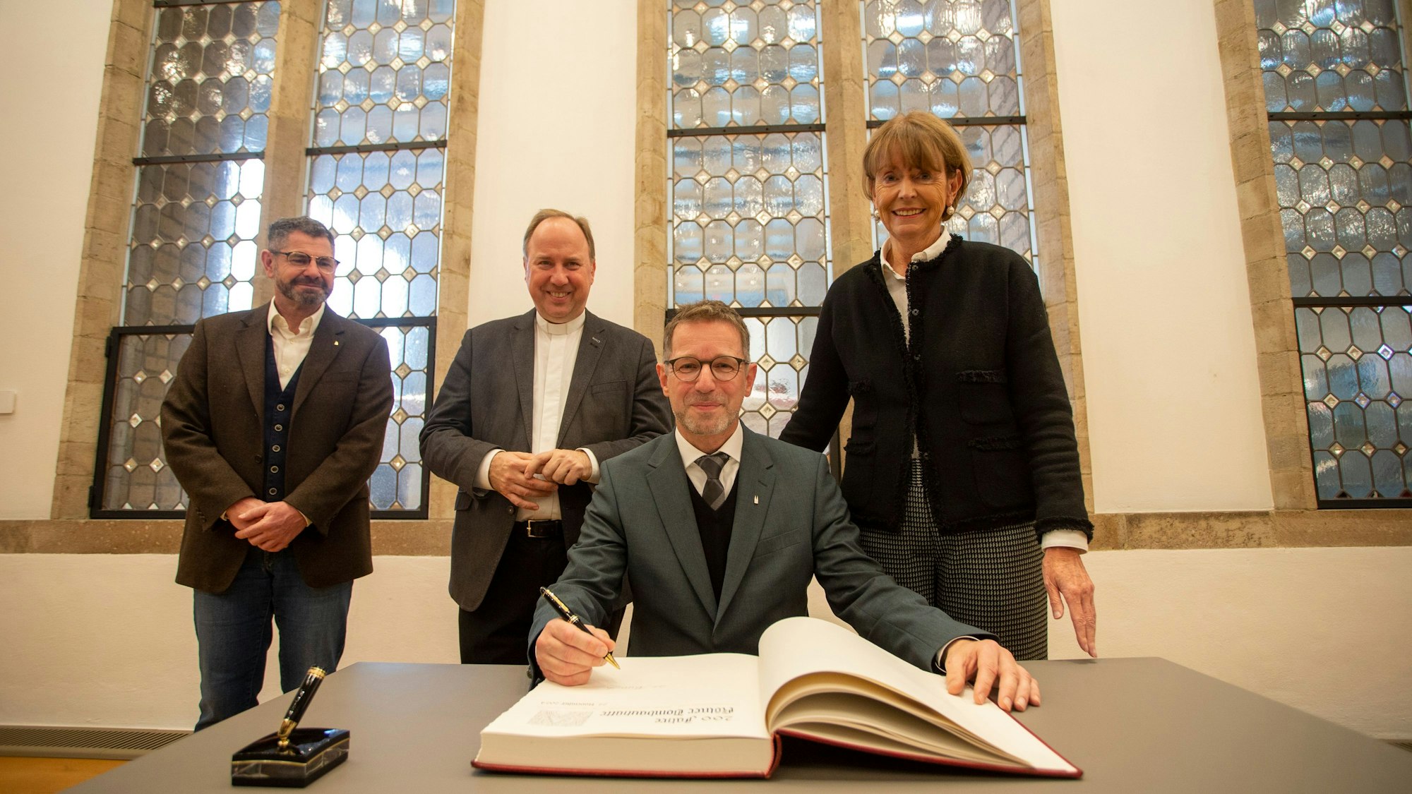 Drei Herren tragen sich ins Gästebuch der Stadt Köln ein.