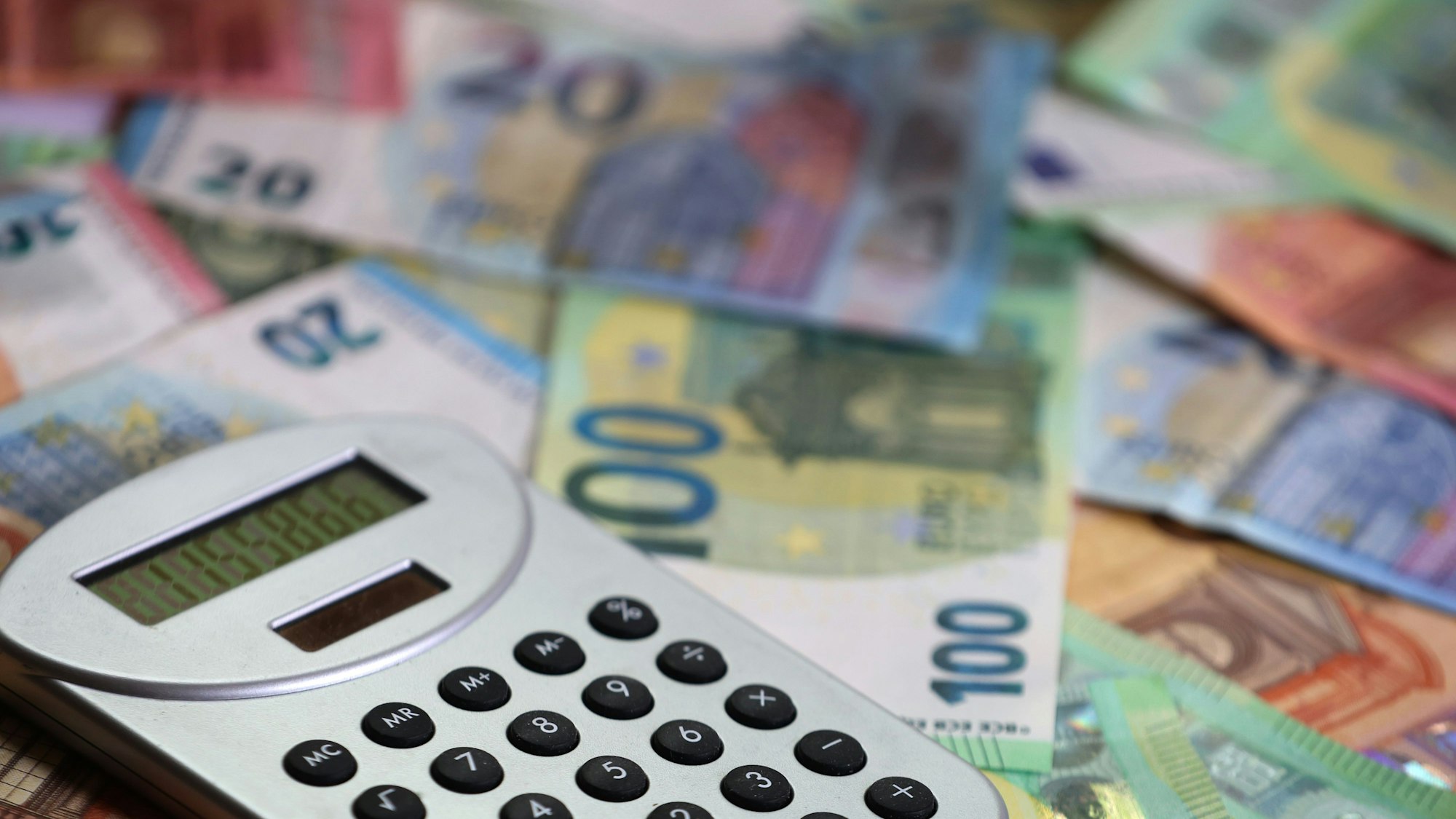 Ein Taschenrechner liegt auf verschiedenen Euro-Banknoten.