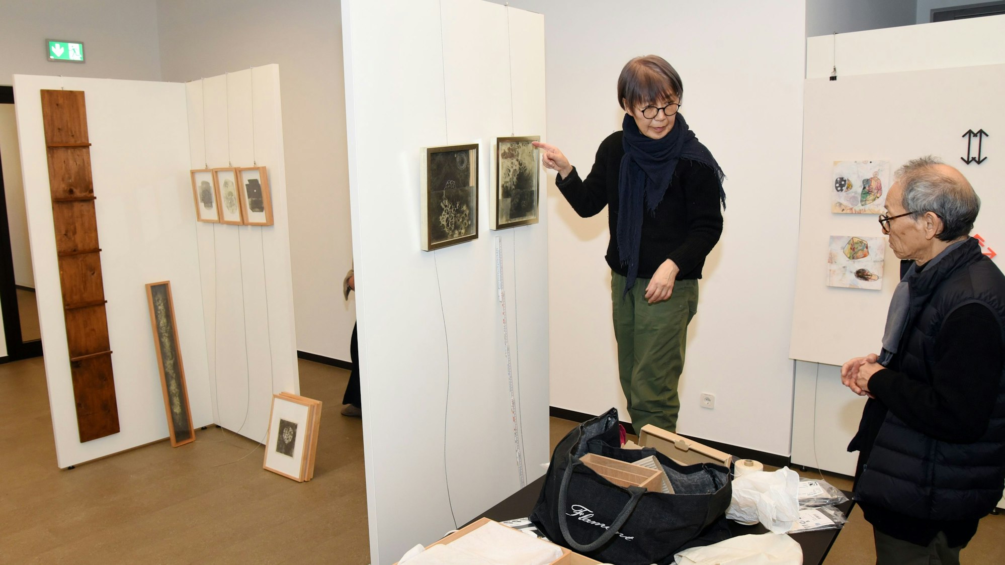 Eine Frau hängt Bilder auf.