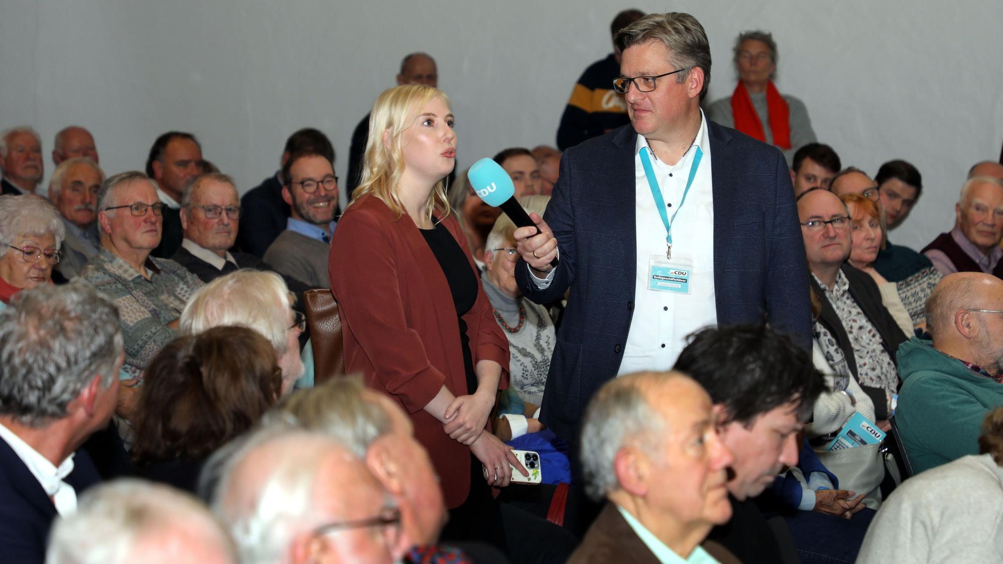 Eine Frau spricht in ein Mikrofon, das CDU-Kreisgeschäftsführer Lennart Höring hält.