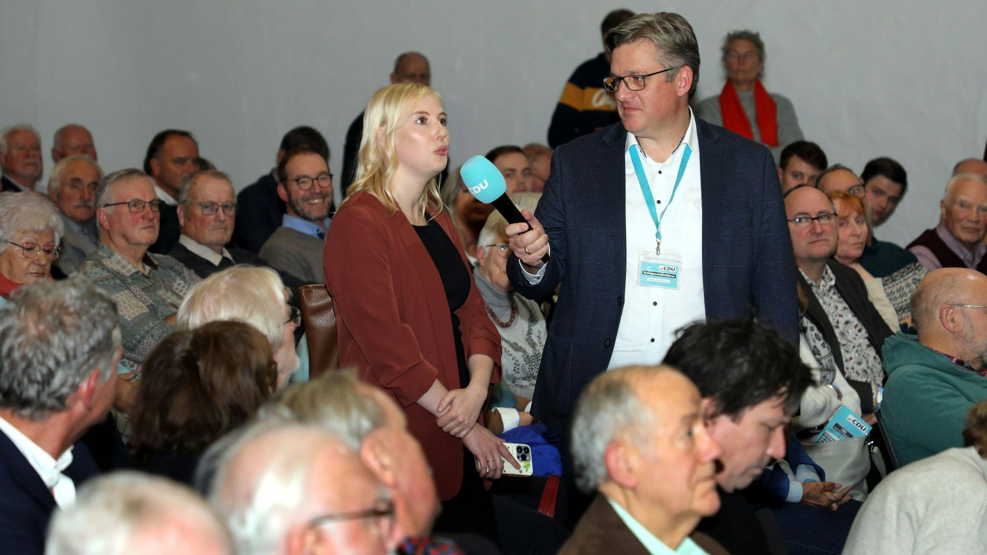 Eine Frau spricht in ein Mikrofon, das CDU-Kreisgeschäftsführer Lennart Höring hält.