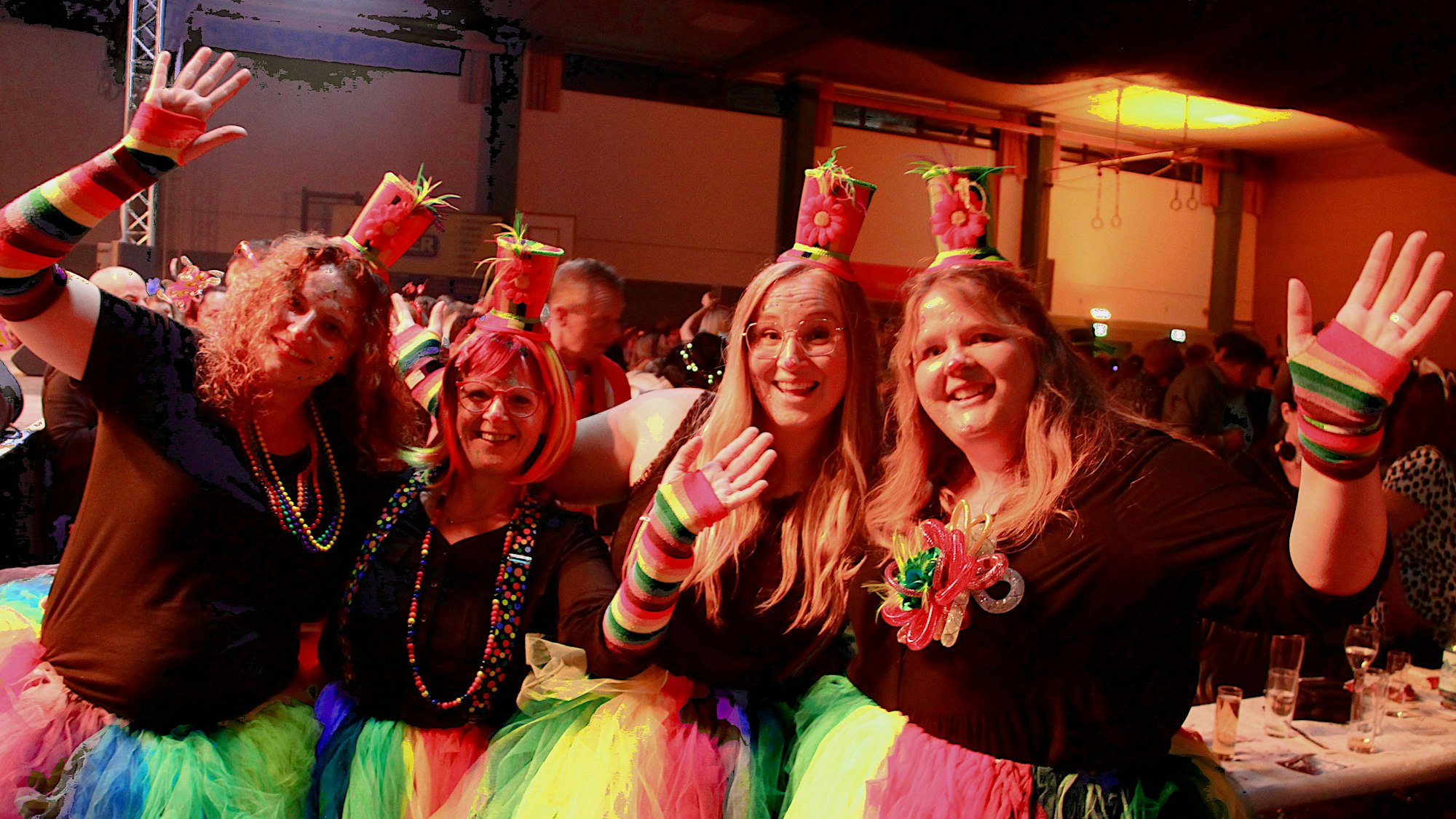 Die Gruppe, gekleidet in Clownskostümen, schunkeln und lachen in die Kamera.