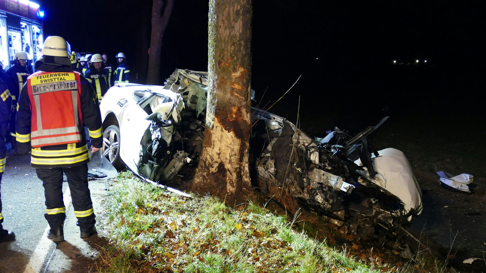 Ein völlig zerstörtes Auto, das gegen einen Baum gekracht ist.