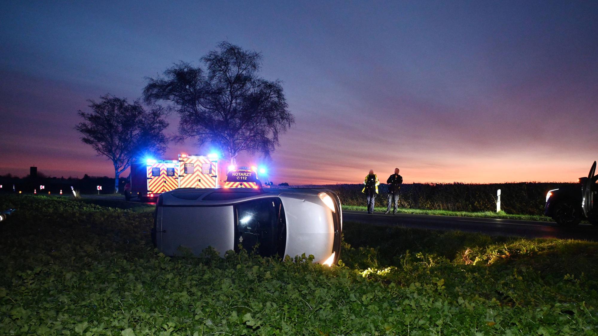 Das Foto zeigt ein verunfalltes Auto, das auf einem Feld auf der Seite liegt.
