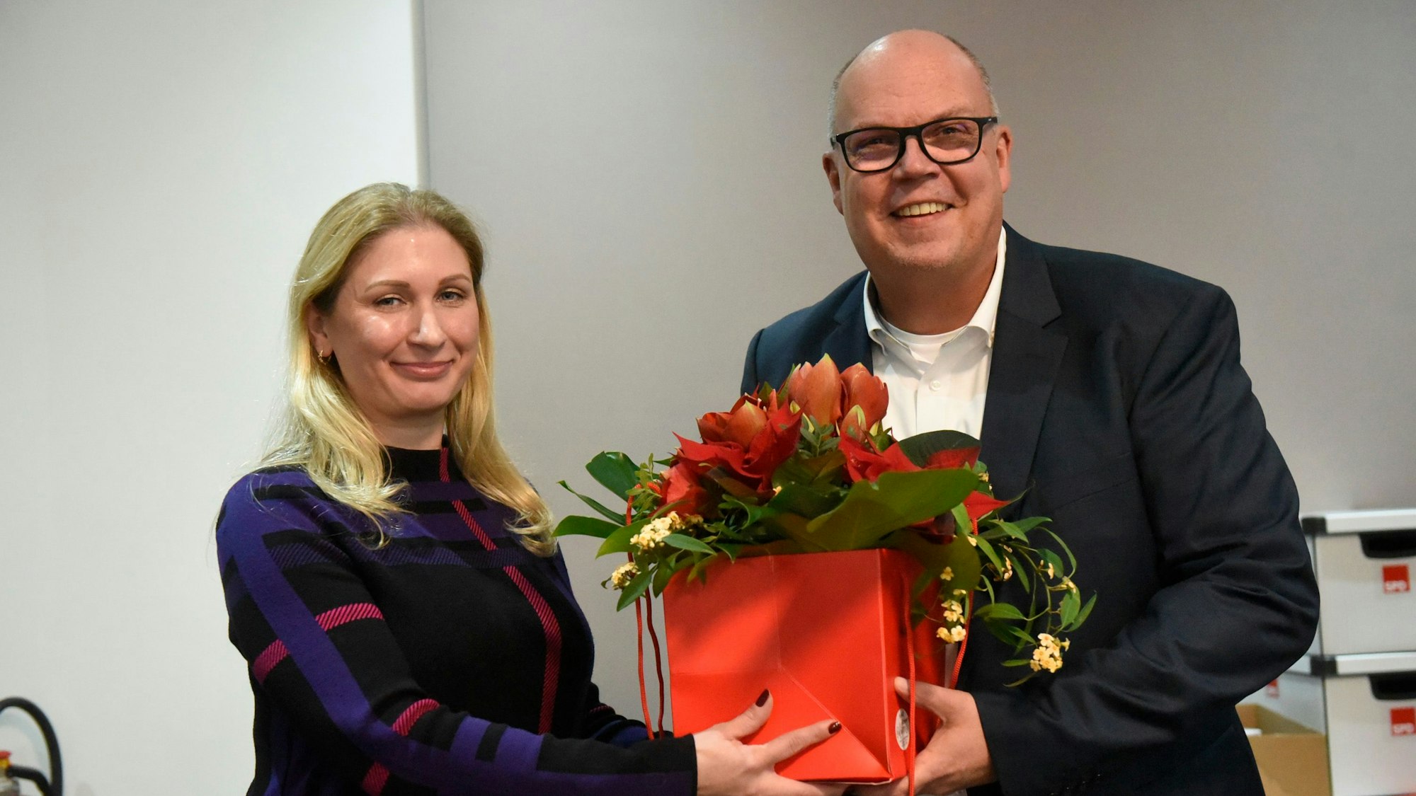 Auf dem Bild ist die Co-Vorsitzende der SPD Frechen zu sehen, die dem neuen Bürgermeisterkandidat einen weihnachtlichen Blumenstrauß überreicht.