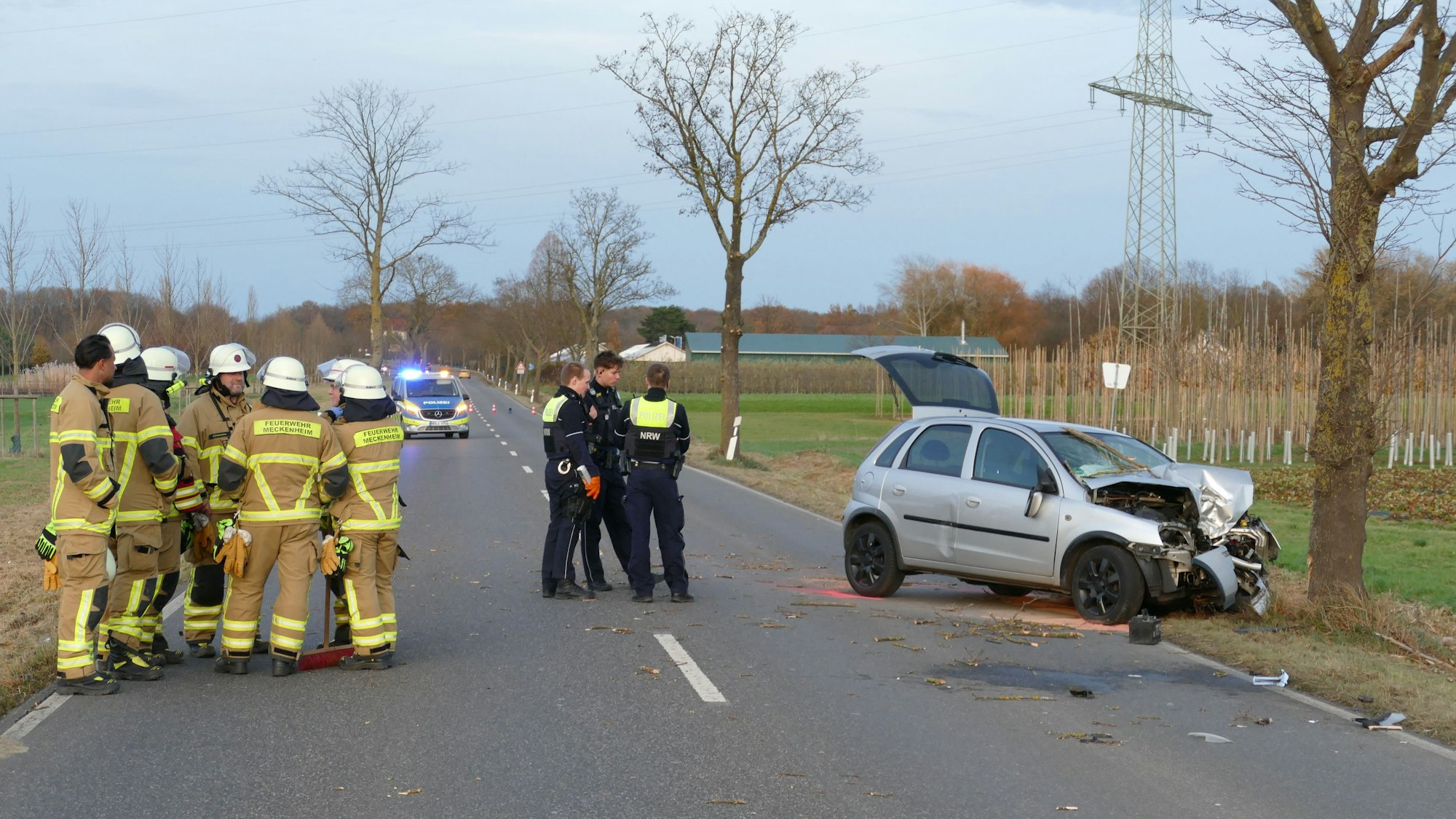 Feuerwehrleute und Polizeibeamte stehen an der Unfallstelle.