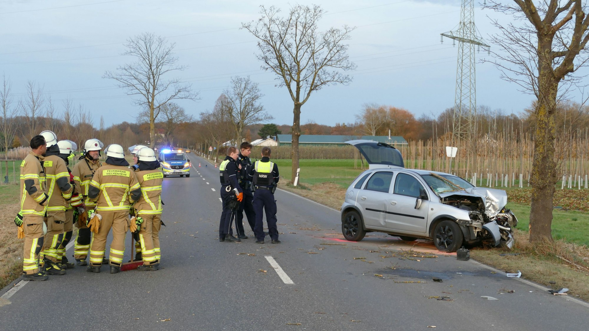 Feuerwehrleute und Polizeibeamte stehen an der Unfallstelle.