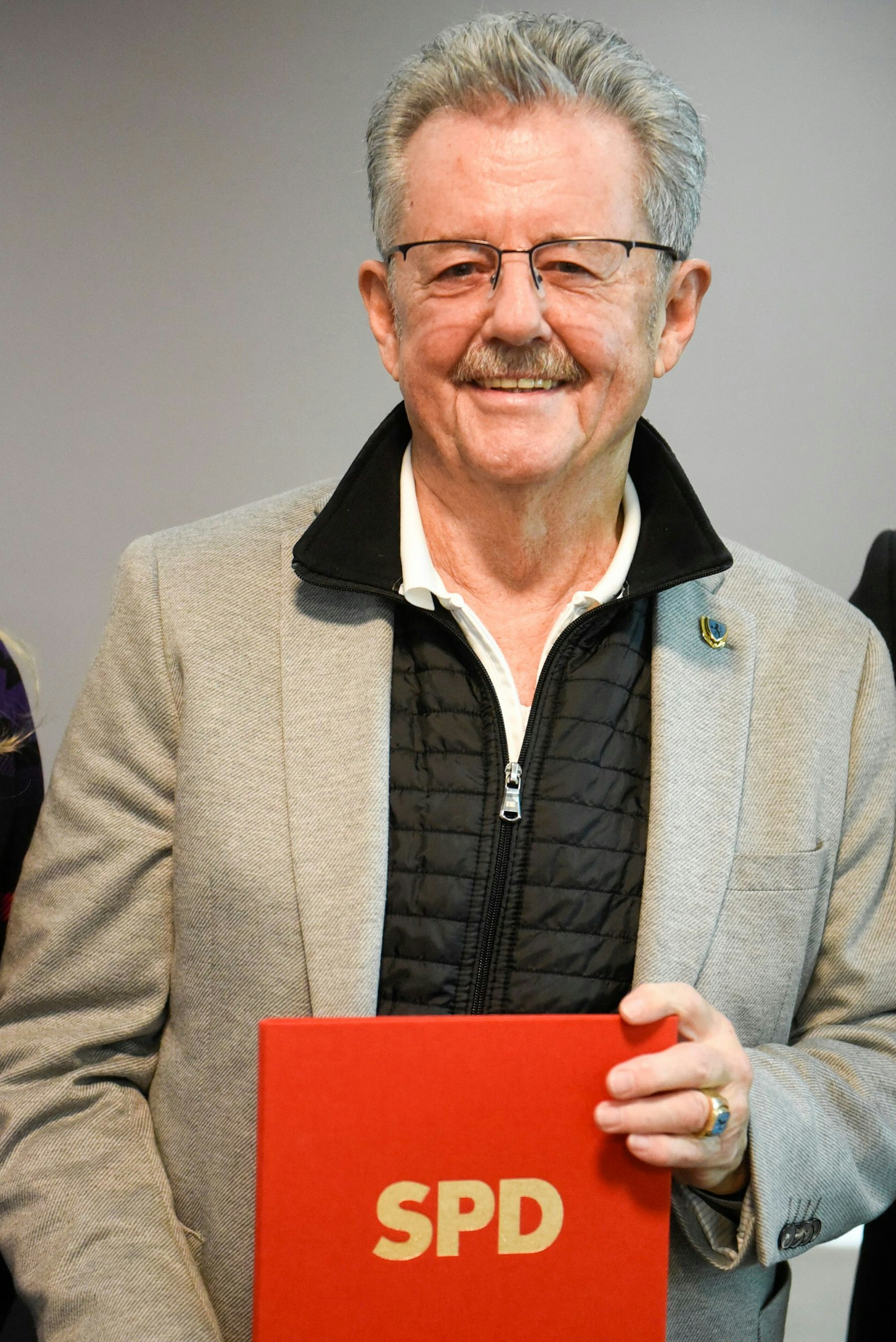 Auf dem Bild ist ein Mann zu sehen, der eine Urkunde für die 50-jährige Mitgliedschaft in der SPD in die Kamera hält.