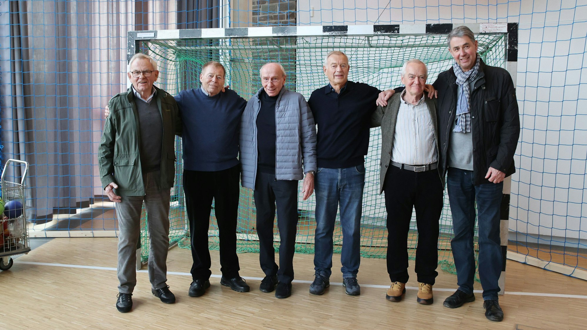 Ehemalige VfL-Handballprofis und -meister stehen für ein Gruppenbild in Handballausstellung zusammen.