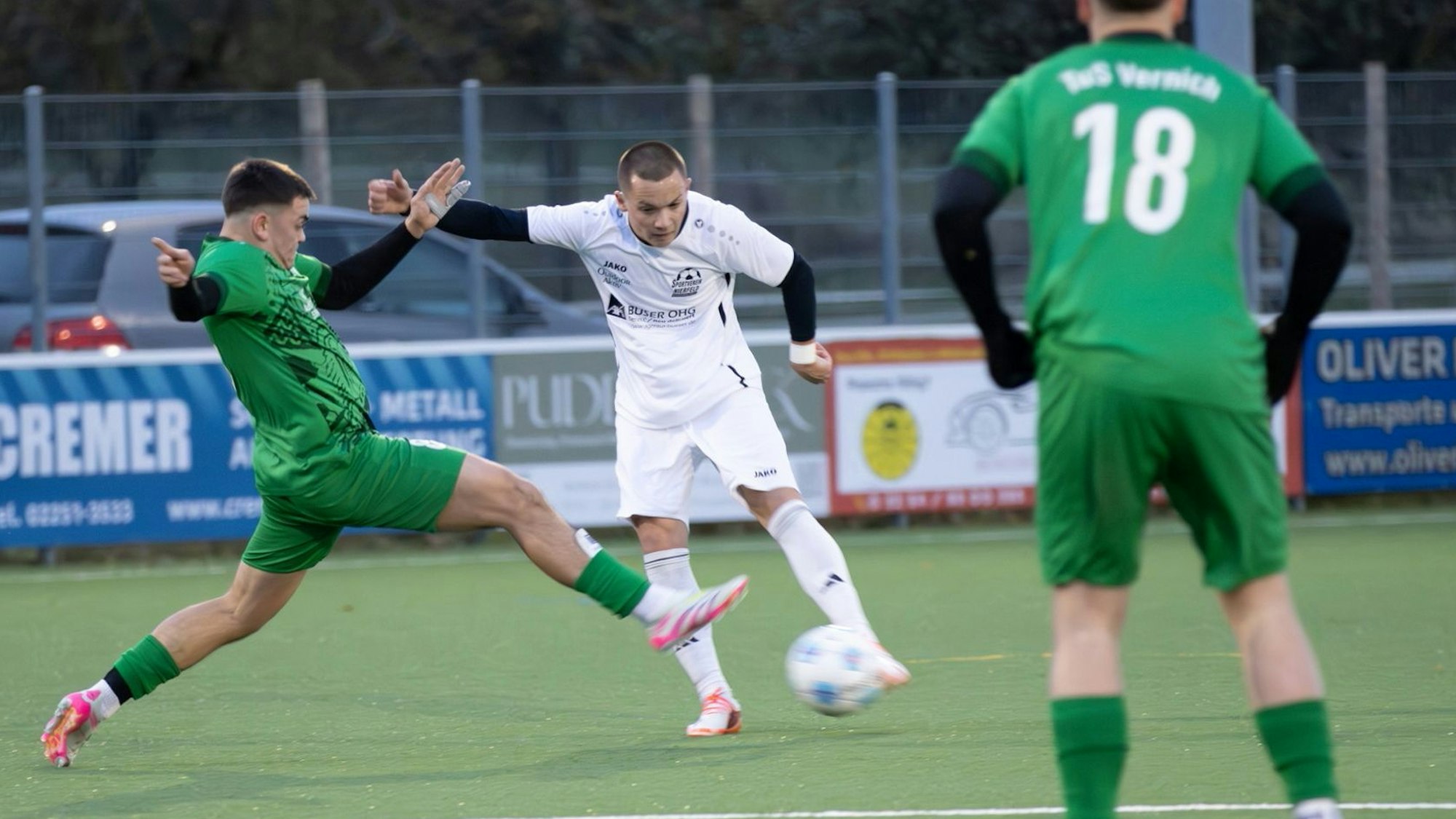 Ein Fußballer schießt, ein Gegenspieler kommt mit ausgestrecktem Bein entgegengeflogen.