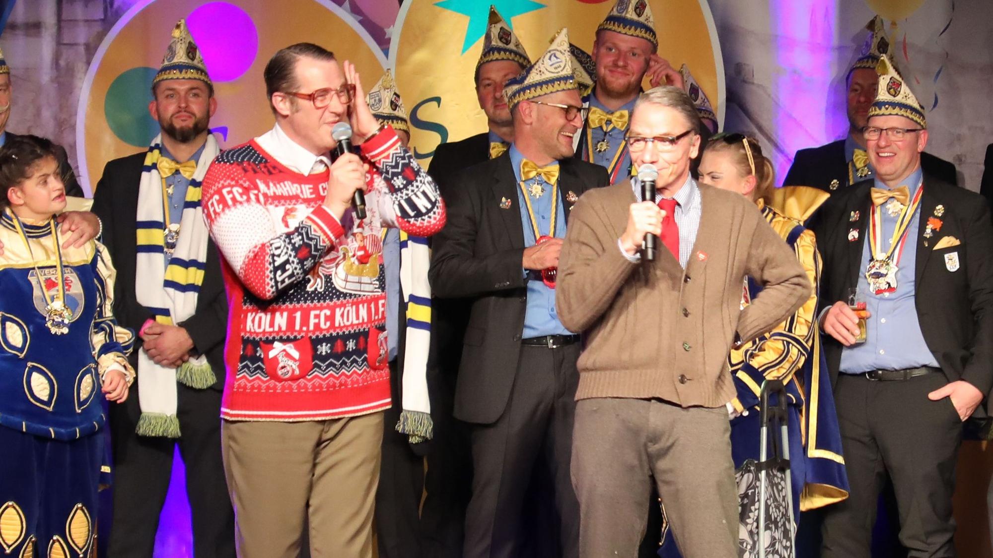 Das Rednerduo Willi und Ernst stehen auf der Bühne bei der Proklamation in der Overather Cyriax-Aula.