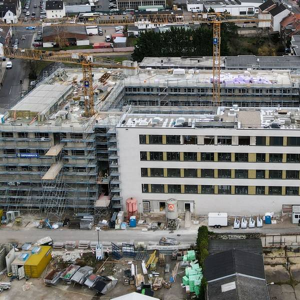 Ein Luftbild zeigt die Baustelle, aus der zwei Kräne herausragen.