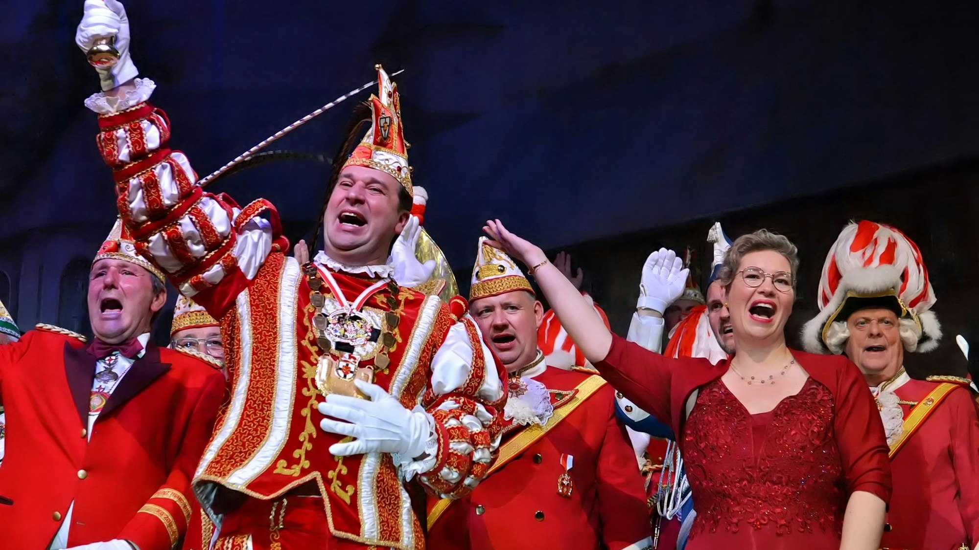 Mit weiteren Karnevalisten steht der Zülpicher Karnevalsprinz in seinem rot-weißen Prinzenkostüm auf der Bühne und grüßt ins Publikum.