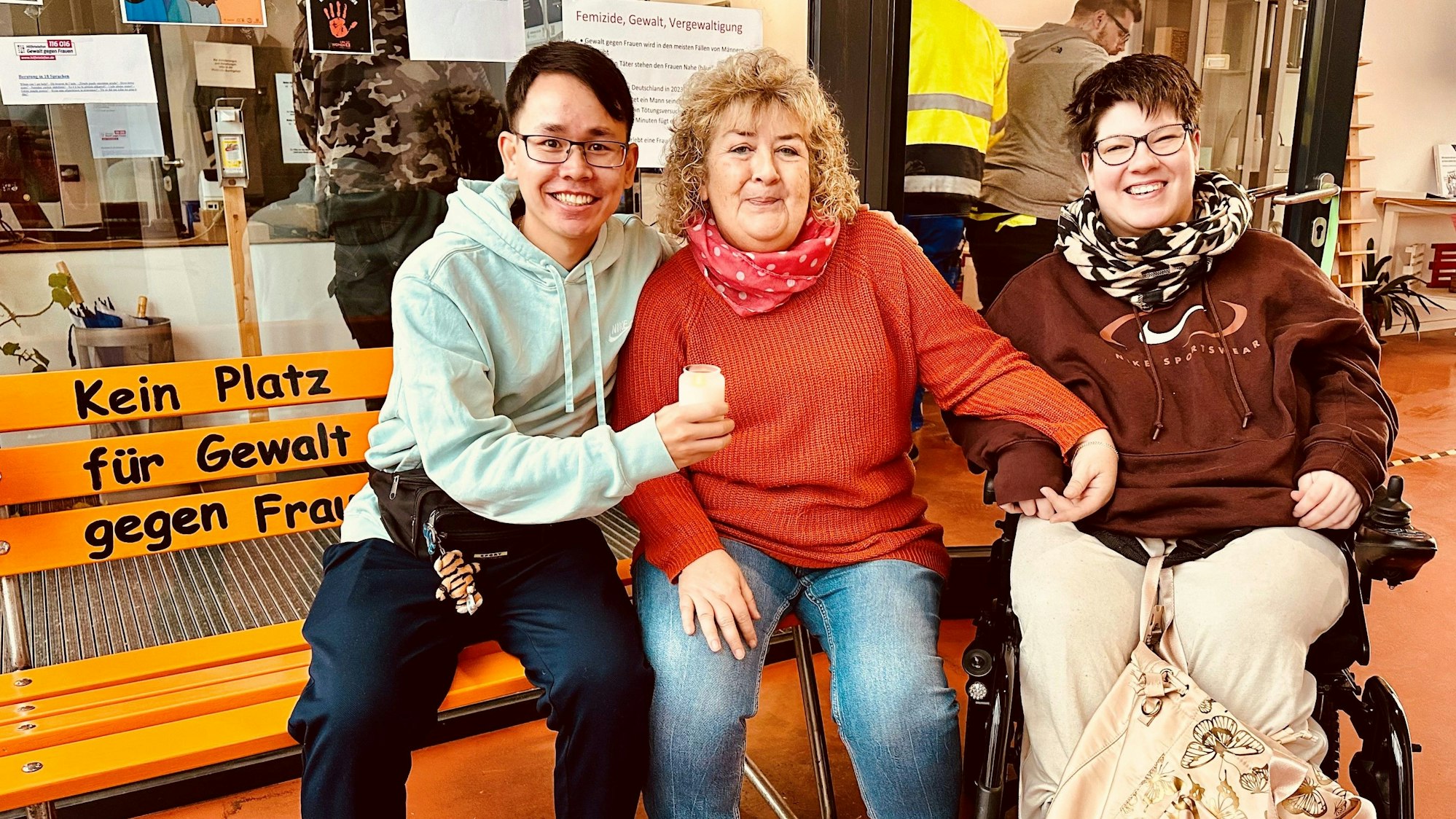 Das Foto zeigt Mitarbeitende der Werkstatt auf und neben einer orangefarbenen Bank mit der Aufschrift „Kein Platz für Gewalt gegen Frauen"“