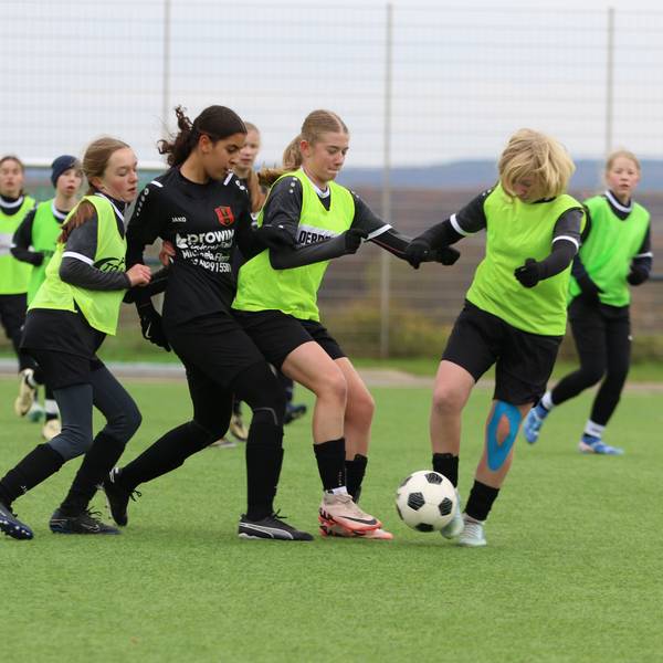 Fußballerinnen im Zweikampf. Da beide Mannschaften schwarze Trikots und Hosen trugen, mussten die Gastgeberinnen grellgrüne Leibchen überziehen.