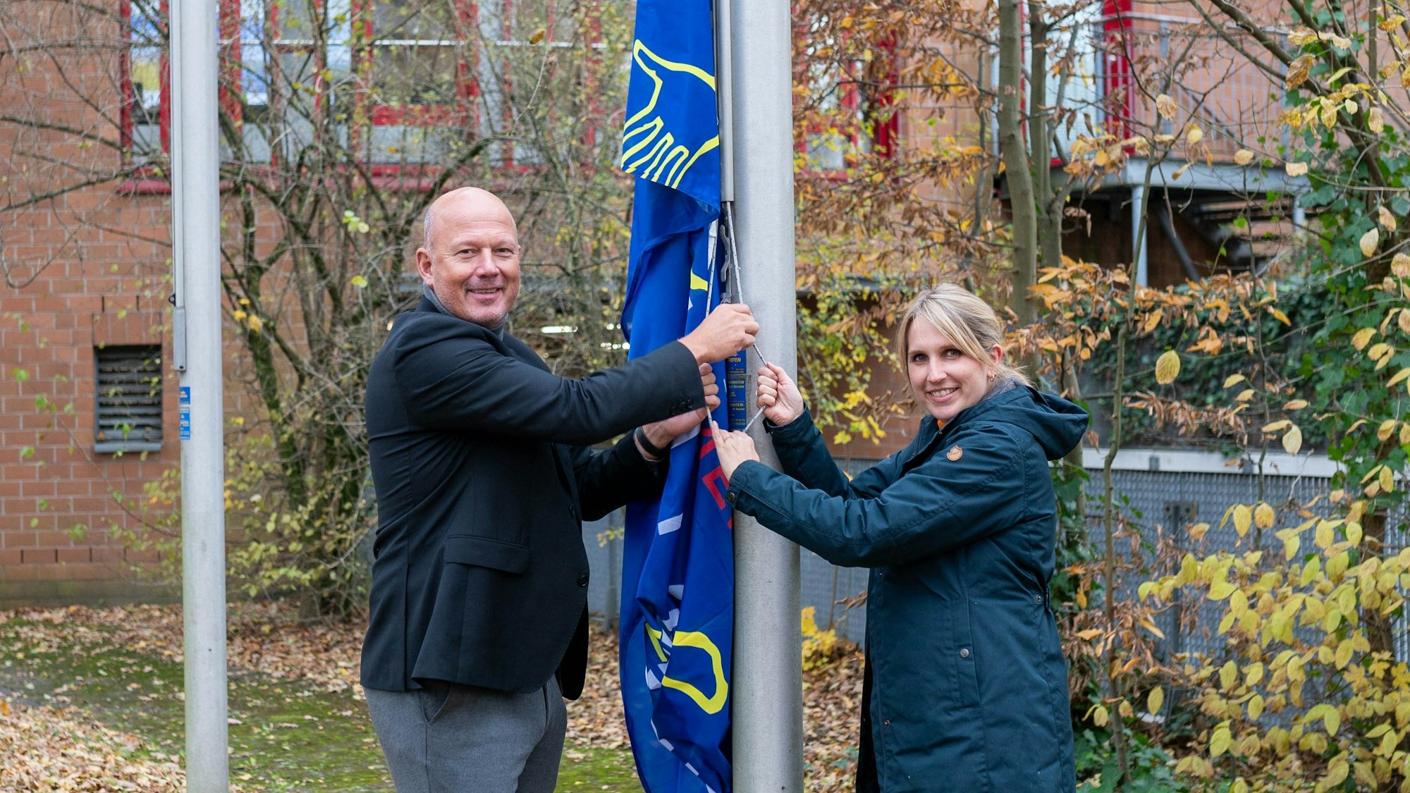 Landrat Frank Rock und Gleichstellungsbeauftragte Julia Willems hissen die Flagge zum Internationalen Tag gegen Gewalt an Frauen.