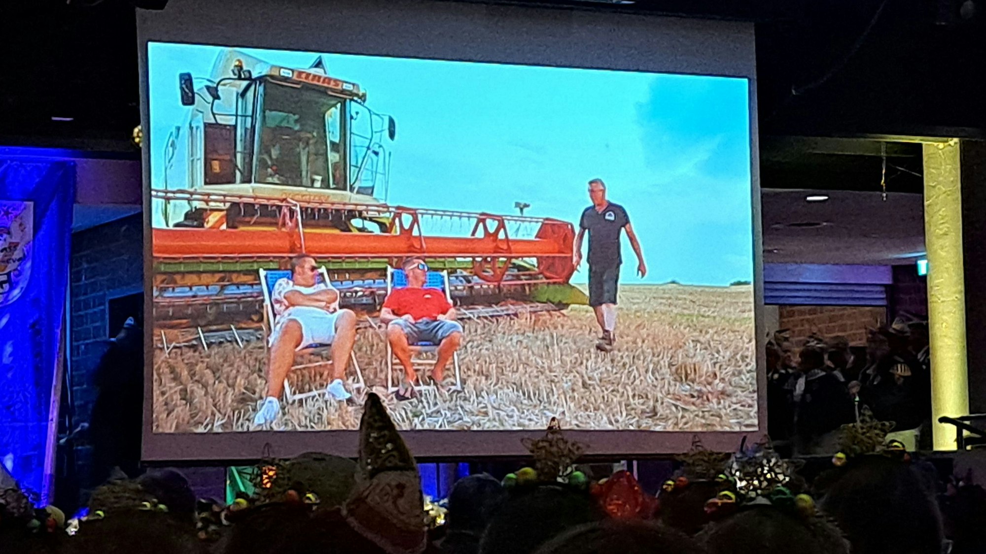 Auf einer Videoleinwand in der Cyriax-Aula sind das Overather Dreigestirn und ein Mähdrescher zu sehen.