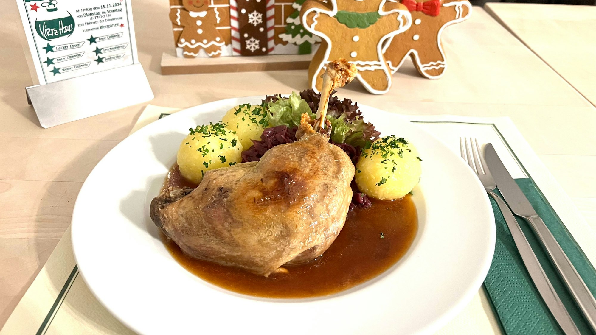 Eine Gänsekeule und Ködel liegen auf einem Teller.