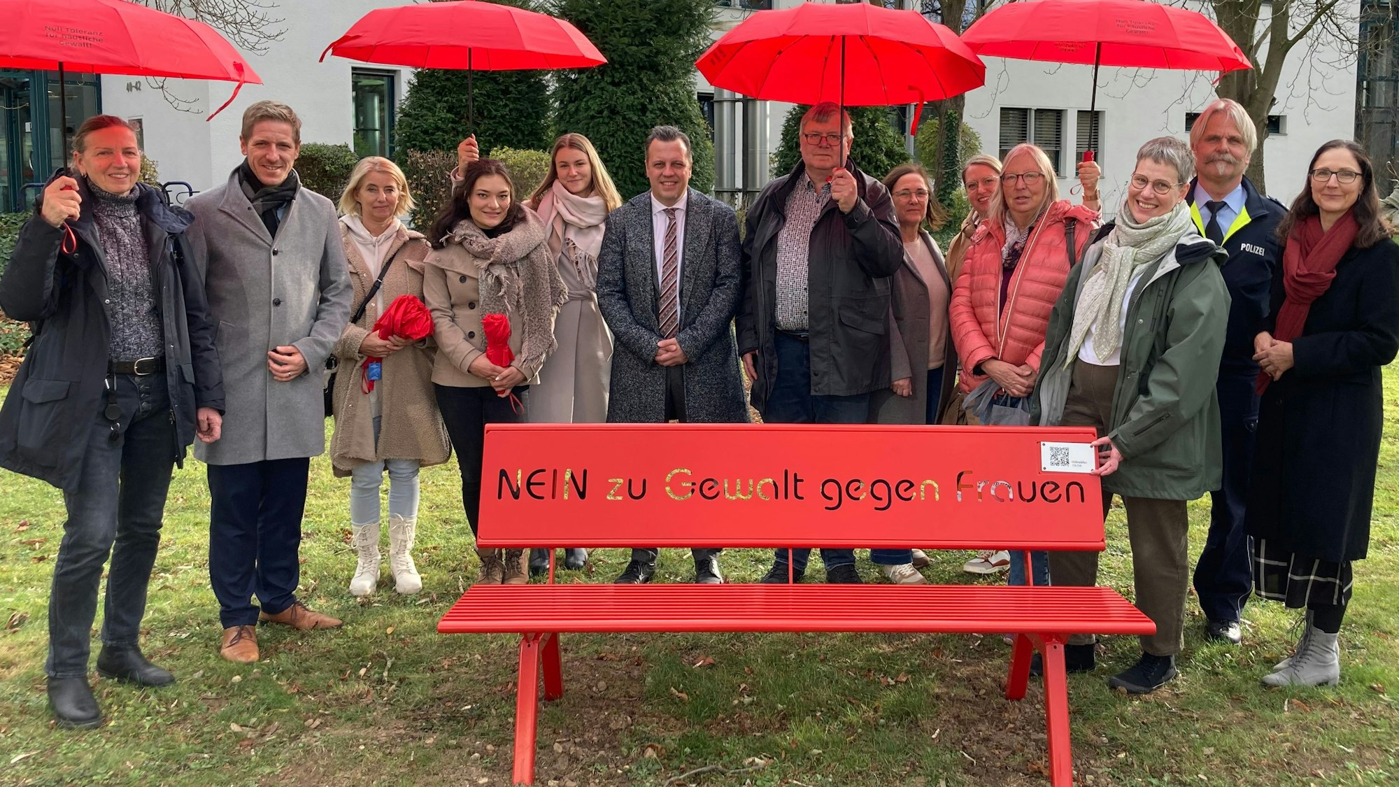 Das Bild zeigt die Initiatoren, die vor dem Amtsgericht in Euskirchen hinter einer roten Bank posieren.