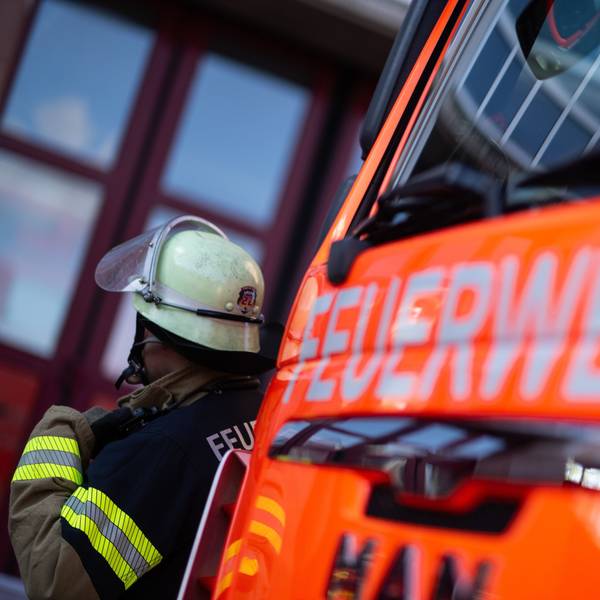 Das Foto zeigt einen Feuerwehrmann vor einem Einsatzfahrzeug mit dem Schriftzug „Feuerwehr“.
