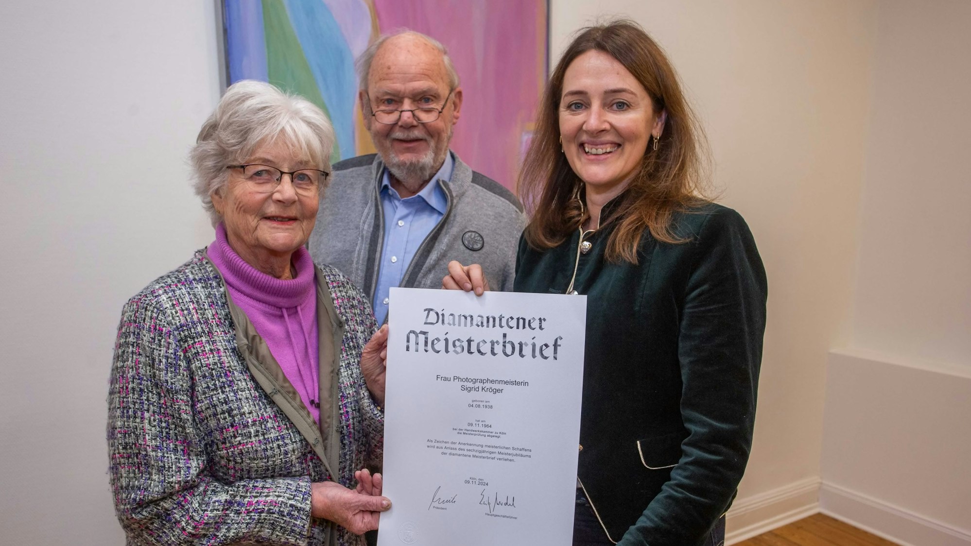 Von Waldbröls Bürgermeisterin Larissa Weber (rechts) hat Sigrid Kröger den diamantenen Meisterbrief der Handwerkskammer zu Köln erhalten, auch Ehemann Klaus freut sich darüber.