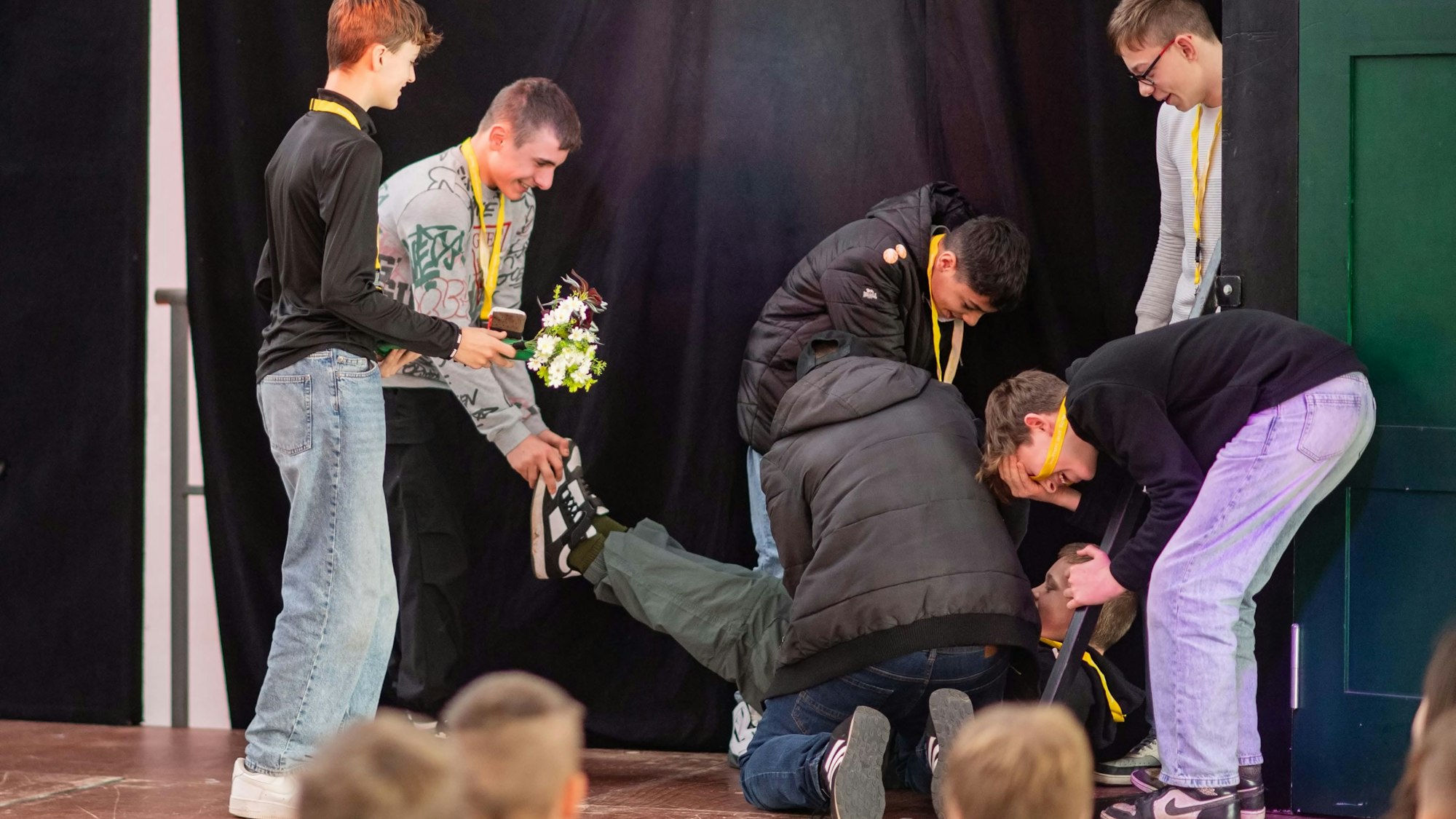 Das Bild zeigt sieben Schüler, die auf der Bühne ein Stück vorführen. Dabei lachen sie.