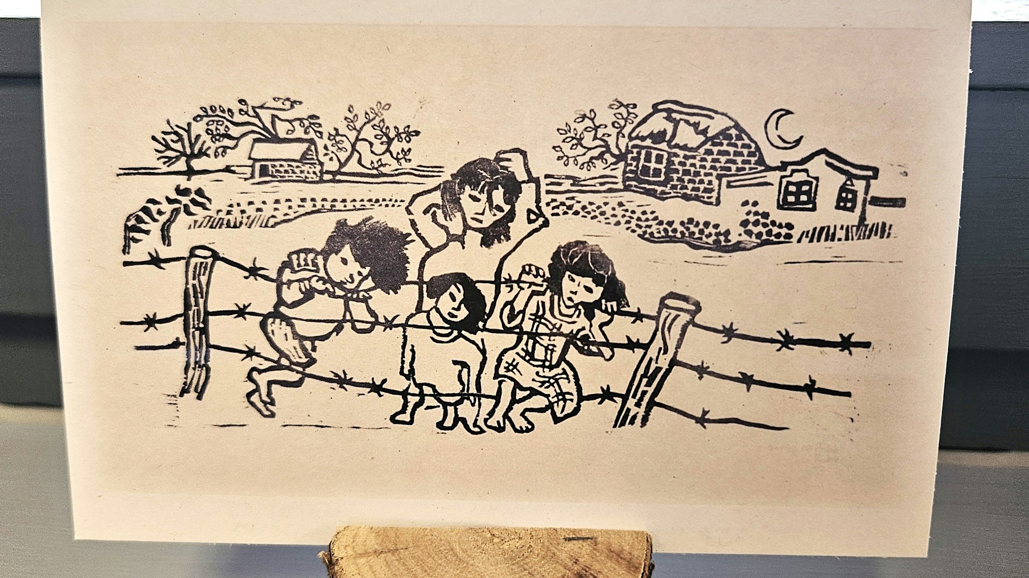 Das Foto zeigt eine Postkarte mit dem Motiv „Kinder am Stacheldrahtzaun“.