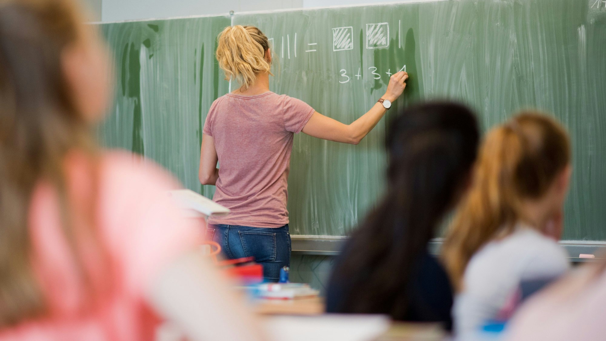 Eine junge Lehrerin schreibt an eine Schultafel im Mathematikunterricht
