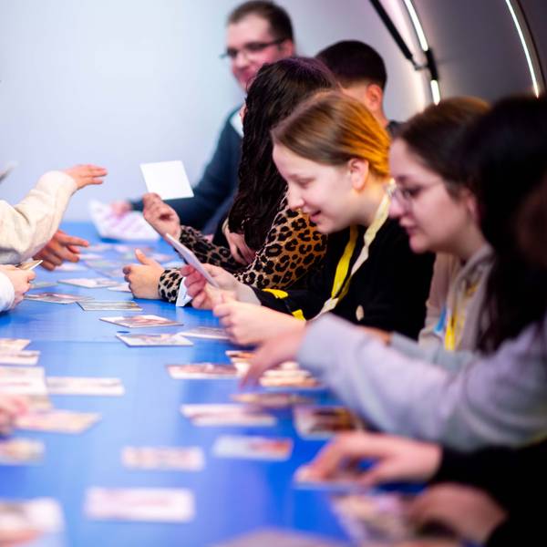 Das Bild zeigt einige Schülerinnen und Schüler, die sich Bilder auf kleinen Karten anschauen.